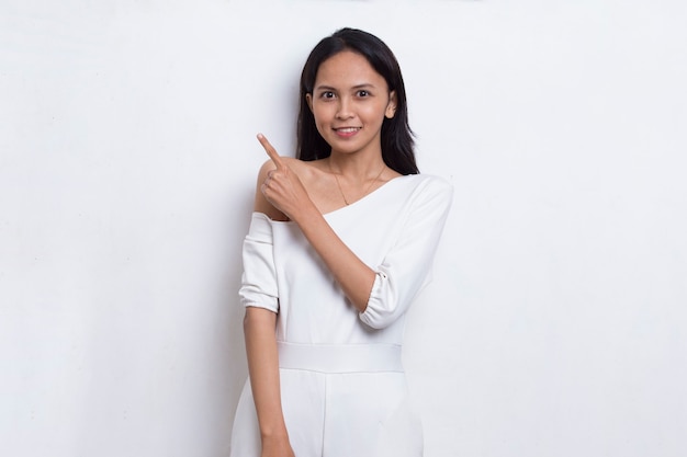 Happy young asian woman pointing with fingers to different directions isolated on white background