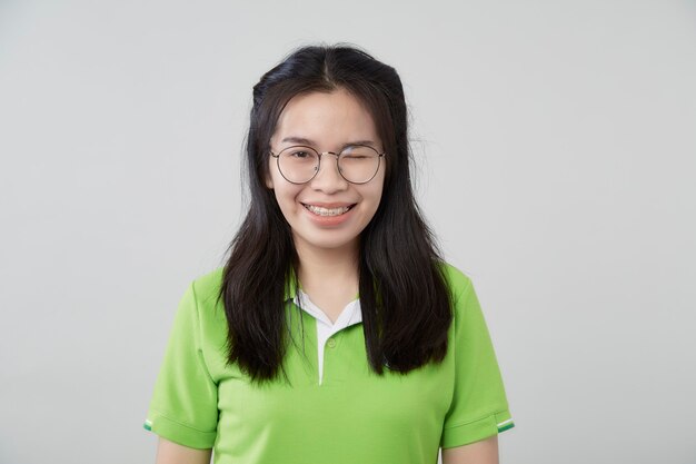 Happy young Asian woman portrait with a green shirt gray background, beautiful Asian confidence teenager