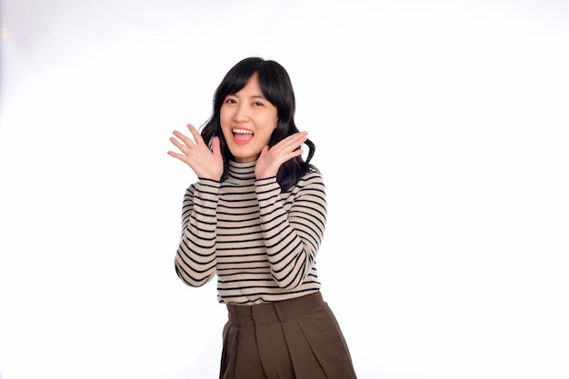 Happy young asian woman professional entrepreneur standing in casual clothing open mouths raising hands shout announcement white background