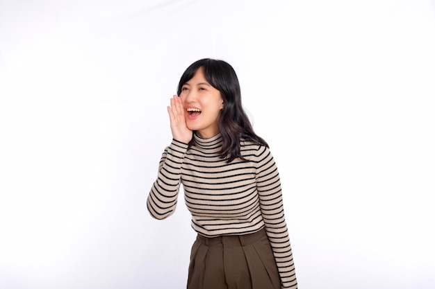 Happy young asian woman professional entrepreneur standing in casual clothing open mouths raising hands shout announcement white background