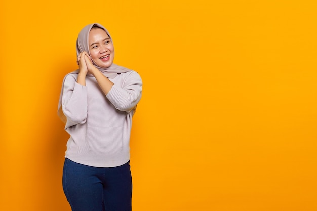 Happy young asian woman rub hands and expect to relish on yellow background