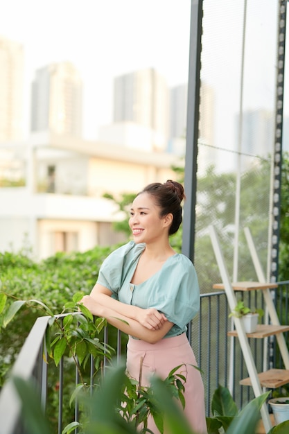 Felice giovane donna asiatica in piedi da solo sul balcone