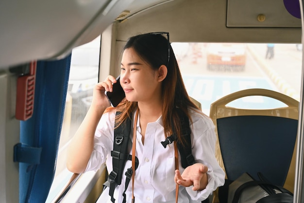 행복한 젊은 아시아 여성은 버스에서 여행하는 동안 휴대 전화로 이야기합니다.