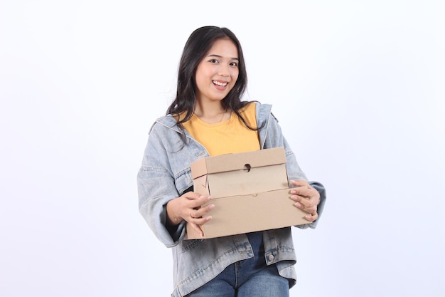 Happy Young Asian woman wearing blue jacket yellow tshirt holding and giving package parcel boxes