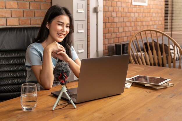 Happy young attractive woman working or learning online through her laptop computer at home in her living room