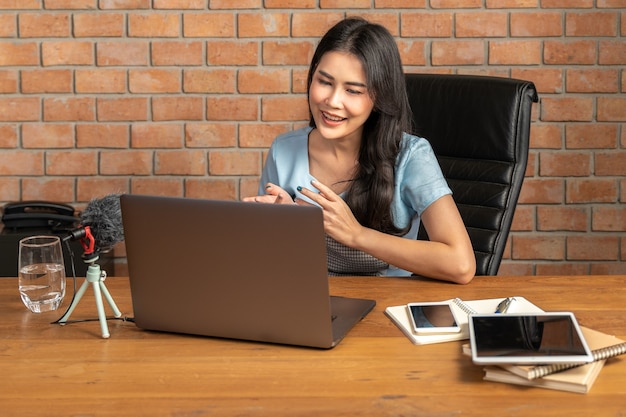 Happy young attractive woman working online through her laptop computer at home in her living room