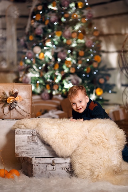 Happy Young Baby Near Christmas Tree With Gifts and mandarines