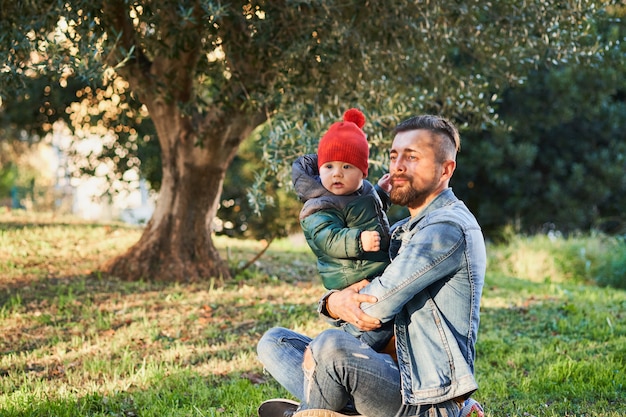 公園で幼い息子と遊んで幸せな若いひげを生やした男