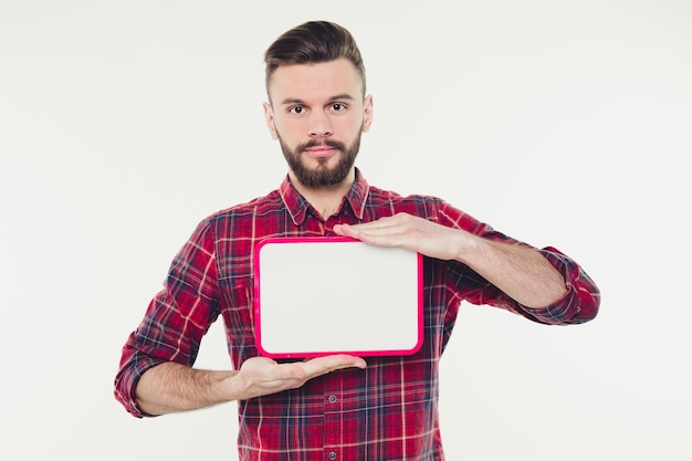 Happy young bearded man showing and displaying white empty placard ready for your text or product or ad