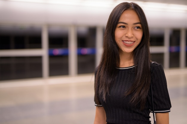 Felice giovane bella donna turistica asiatica alla stazione della metropolitana