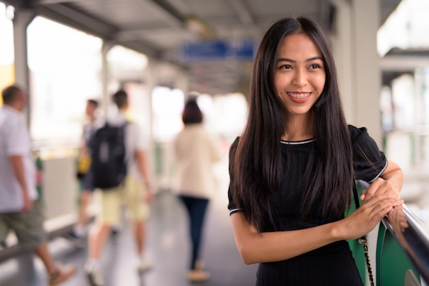 歩道橋を考えて幸せな若い美しいアジア観光女性