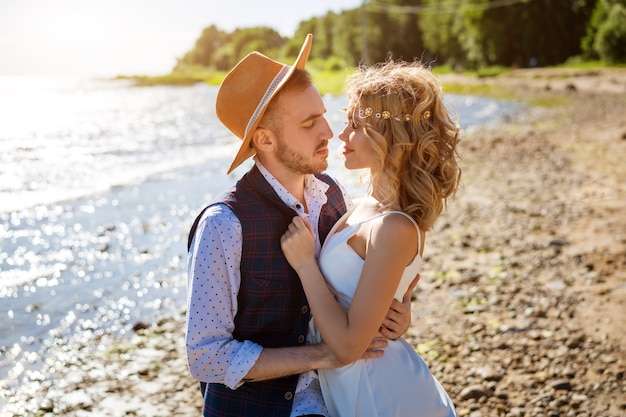 Happy young beautiful couple in arms on the beach on a Sunny day.