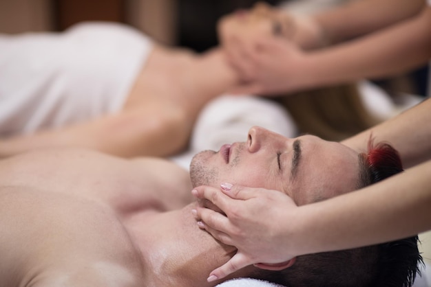 happy young beautiful couple enjoying head massage at the spa