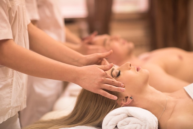 happy young beautiful couple enjoying head massage at the spa