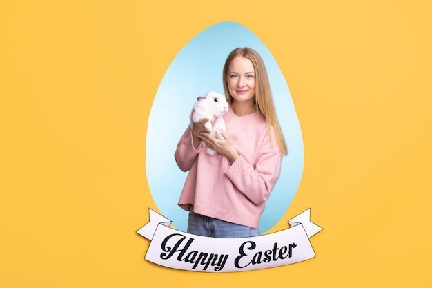 Happy young beautiful female in pink sweater holding easter bunny