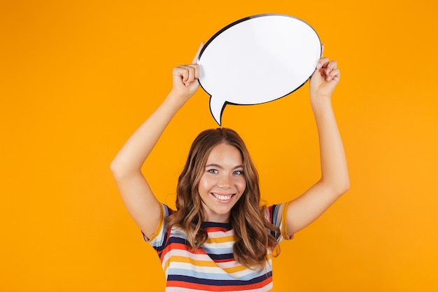 Happy young beautiful girl posing isolated over yellow space holding speech bubble.