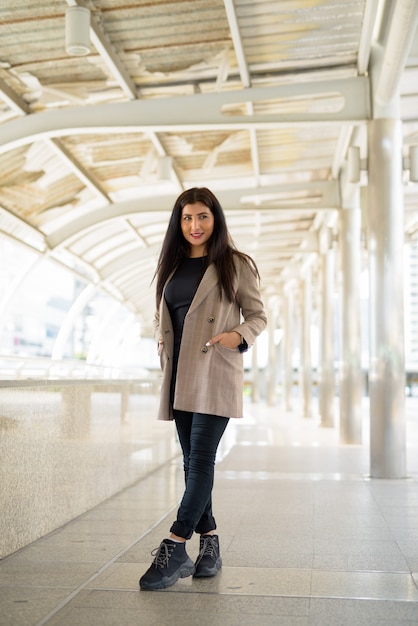 happy young beautiful Indian businesswoman thinking in the city