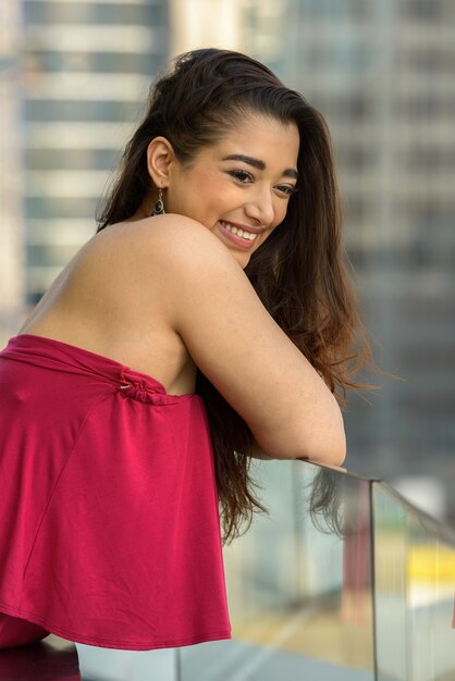 Happy young beautiful Indian woman looking at view of the city