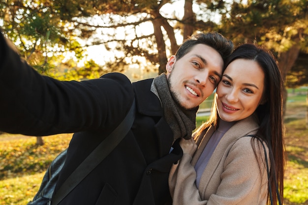 happy young beautiful loving couple posing walking outdoors in park nature take selfie .