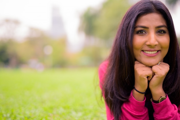 Happy young beautiful Persian woman relaxing at the park