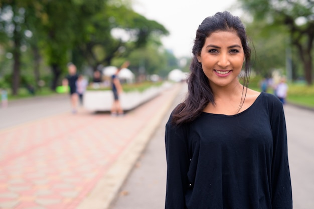 Happy young beautiful Persian woman relaxing at the park