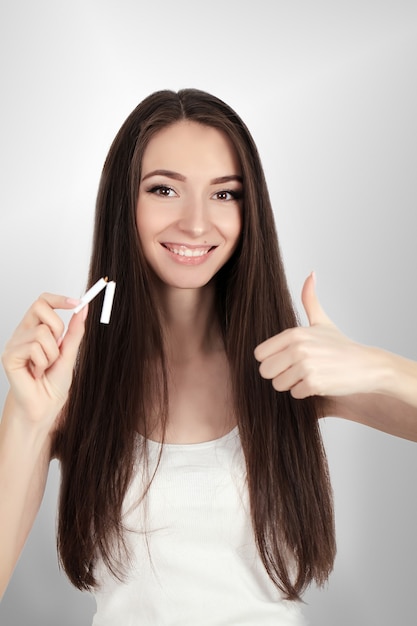 Happy young beautiful woman holding a broken cigarette