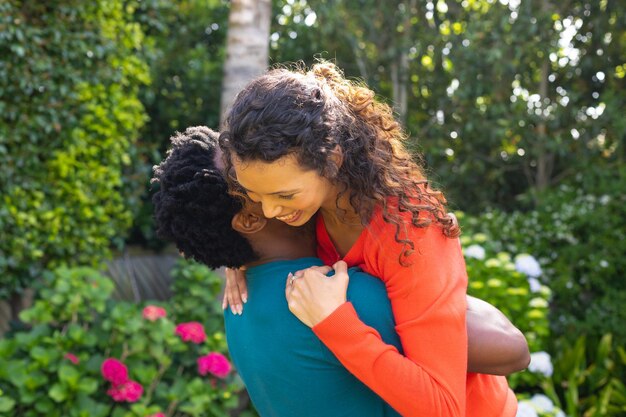 Photo happy young biracial couple hugging while embracing in the garden