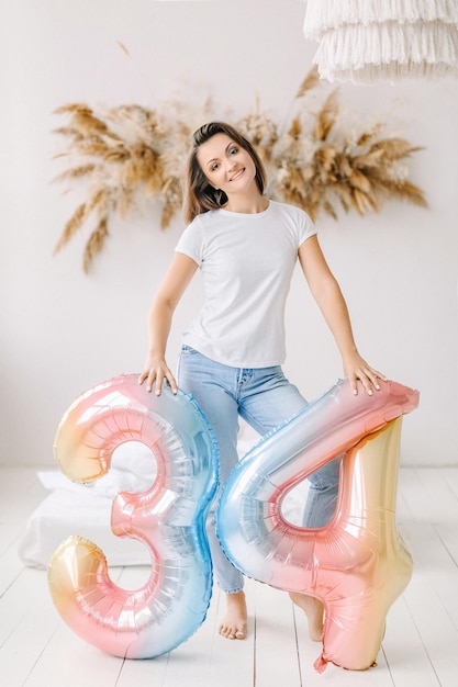 Foto felice giovane donna di compleanno trenta e quattro palloncini decorazioni per la festa di compleanno