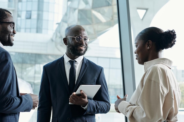 Happy young black businessman in formalwear looking at female colleague