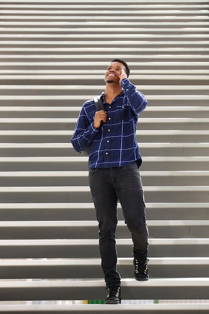 Happy young black man on stairs talking on mobile phone 