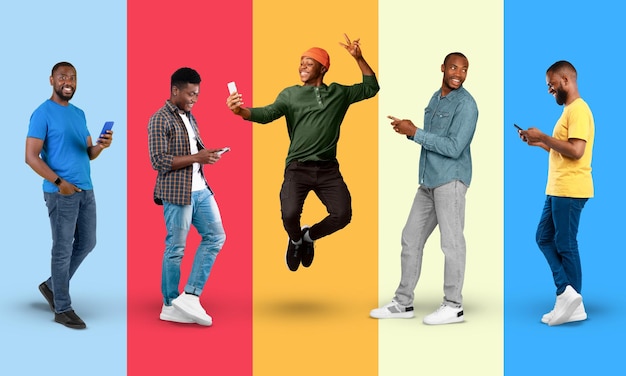 Happy young black men in casual jumping typing on smartphone take selfie isolated on colorful background