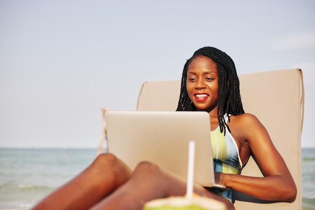 Happy young Black woman on chaise-lounge