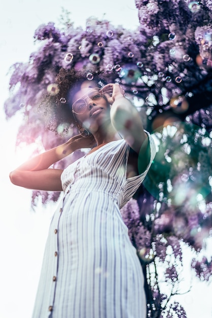 Happy young black woman surrounded by flowers