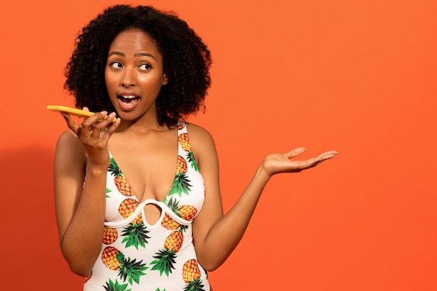 Happy young black woman in swimsuit using cell phone