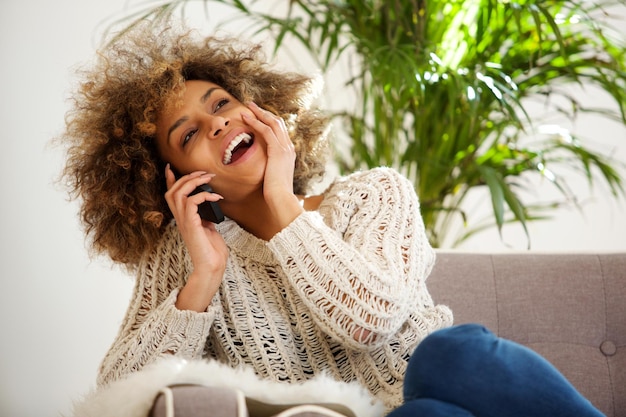 집에서 휴대폰으로 이야기하는 행복한 젊은 흑인 여성