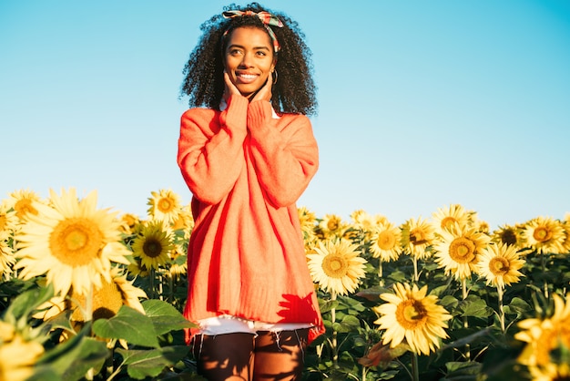 Photo happy young black woman walking in a sunflower field