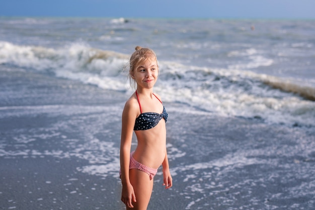 Happy young blonde girl having fun at the dream beach with big white waves