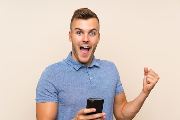 Happy Young blonde man using mobile phone