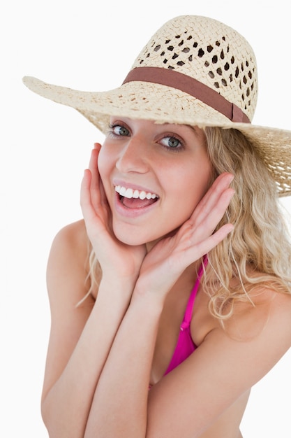 Happy young blonde woman looking at the camera with her hands on her cheeks