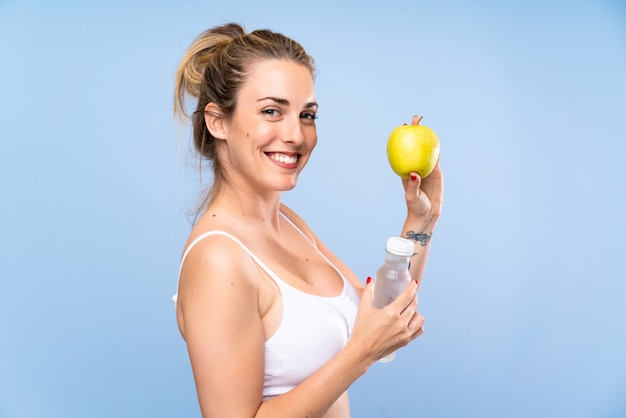 Happy Young blonde woman with an apple and a bottle of water