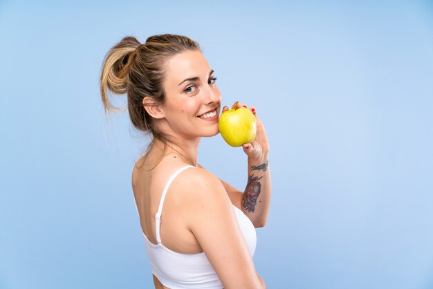 Счастливая молодая белокурая женщина с яблоком