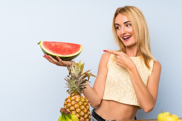 Happy  Young blonde woman with lots of fruits