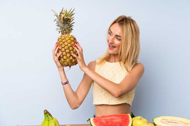 Happy  Young blonde woman with lots of fruits