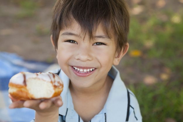 Счастливый молодой мальчик hyolding гамбургер в парке