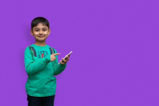 Фото Счастливый молодой мальчик в рубашке, указывая вверх и держа белую руку, глядя в камеру на изолированном фоне и копируя пространство