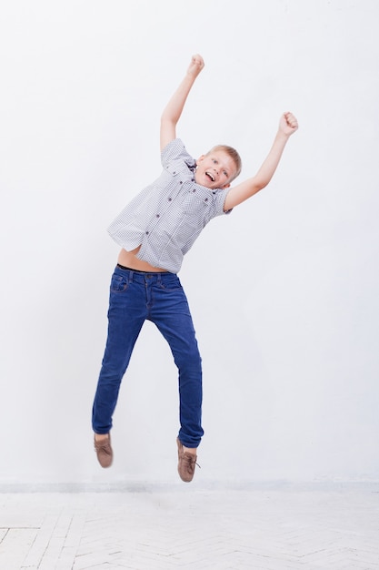 Happy young boy jumping on white background