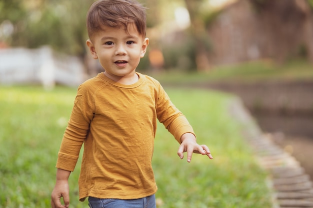 Фото Счастливый молодой мальчик, играя на открытом воздухе в парке