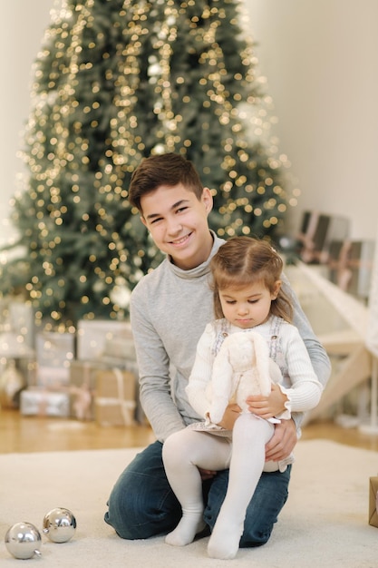 Happy young boy with his niece play in front of fir tree christmas mood