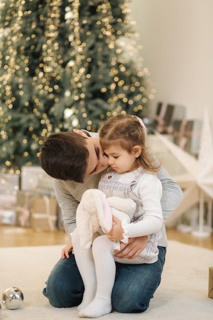 姪と一緒に幸せな少年がモミの木のクリスマス気分の前で遊ぶ