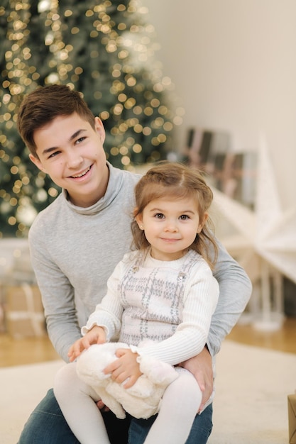 姪と一緒に幸せな少年がモミの木のクリスマス気分の前で遊ぶ